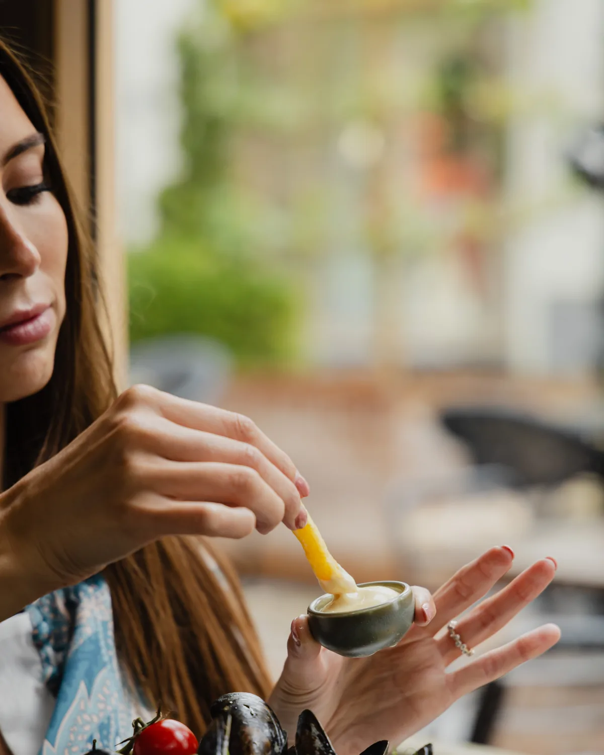 A guest dipping a fry in mayonnaise over a pot of mussels at Maasmechelen Village