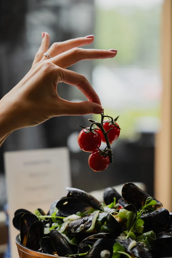 Cherry tomatoes over a pot of mussels